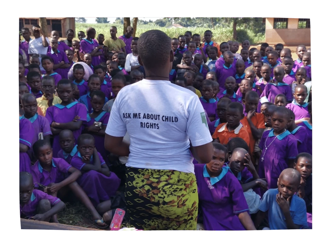 A teenage child in Uganda is stood in front of a group of school children talking about child rights