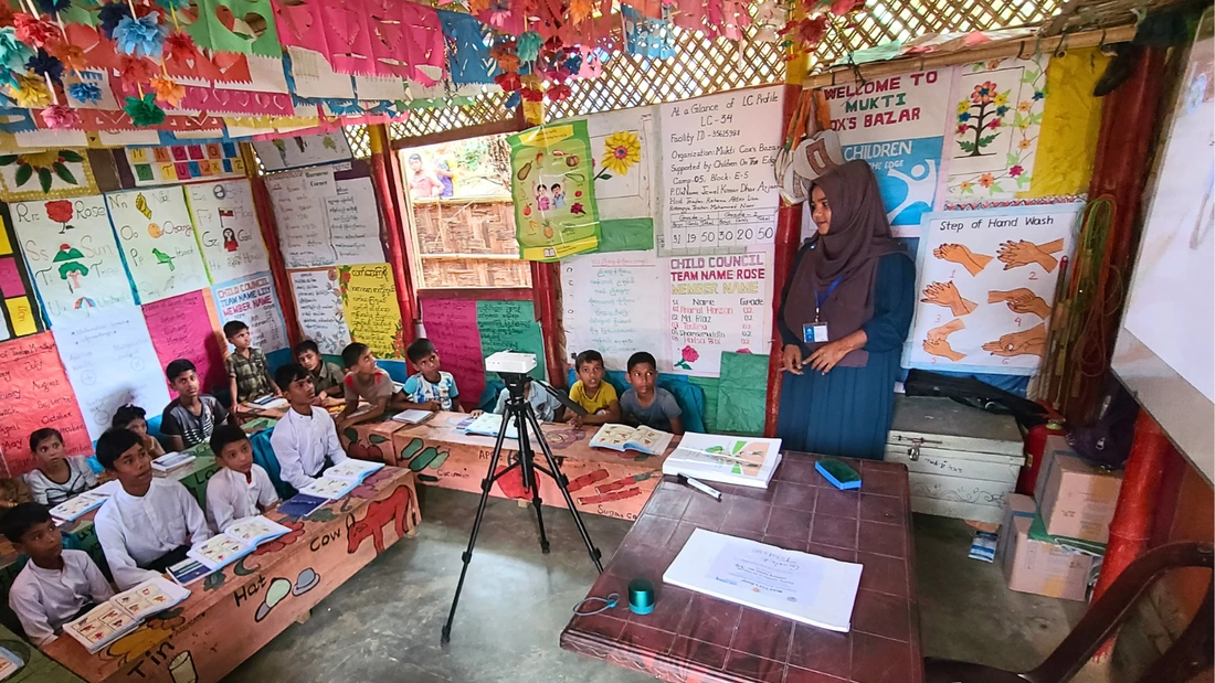 A class in Kutupalong Bangladesh is sat looking at a video screen