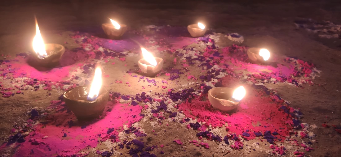 Diwali candles lit in pink Rangoli powder pattern