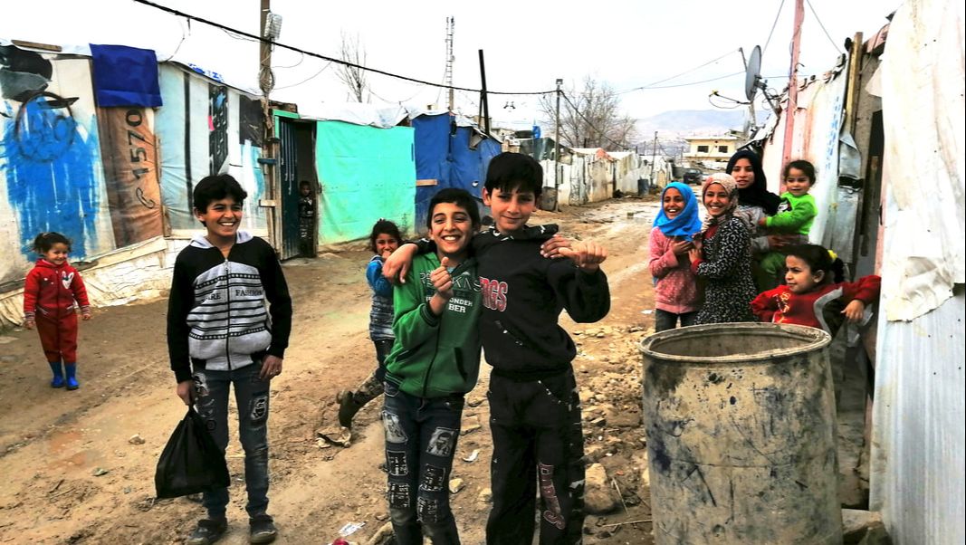 A group of Syrian refugee children laughing for the camera from the informal settlement where they live in Bekaa Valley, Lebanon. 
