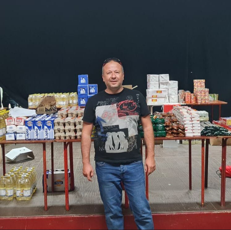Marius, a middle aged white man is standing in front of a table of supplies at the drop in centre