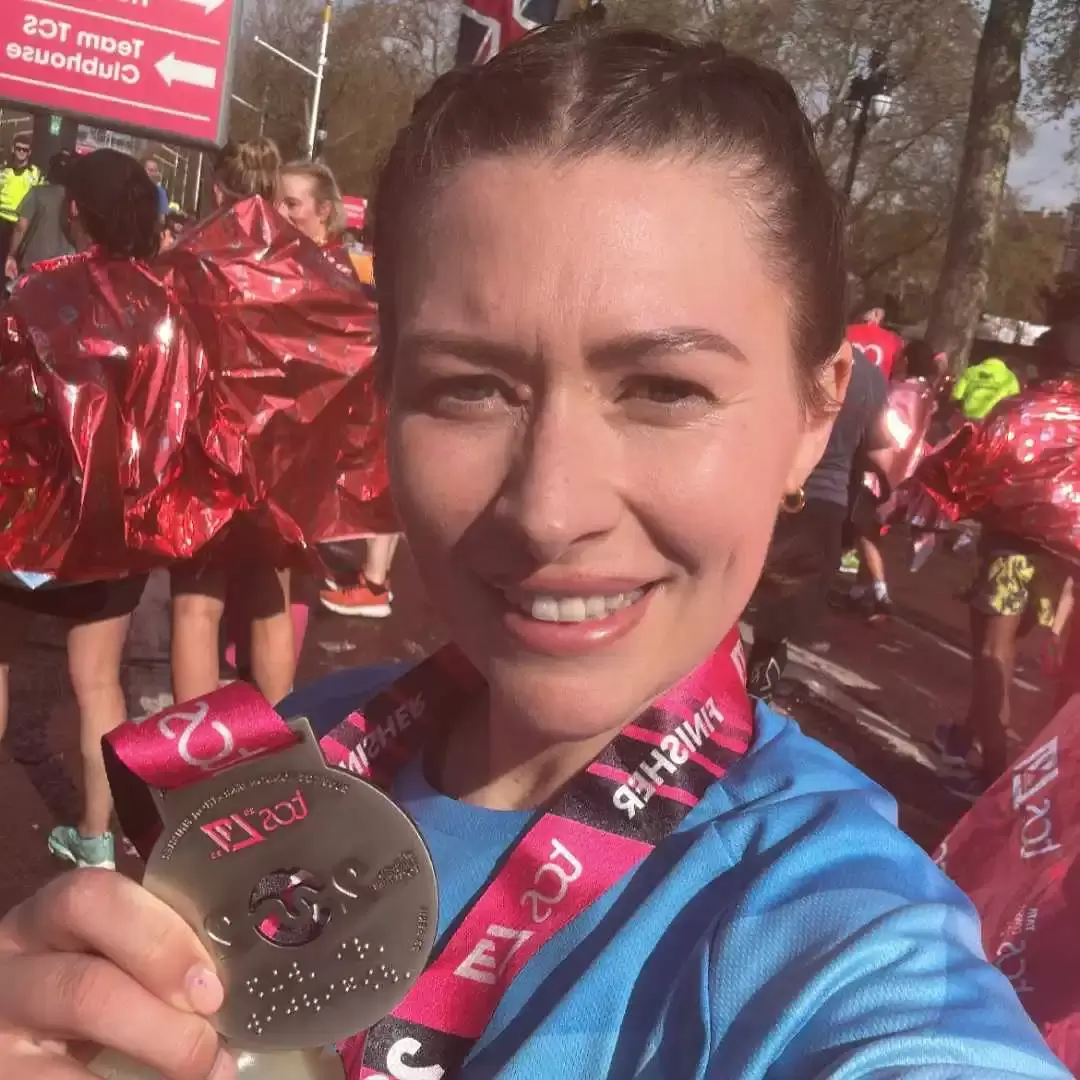 Kelly holding up her medal at the finish of the London Marathon