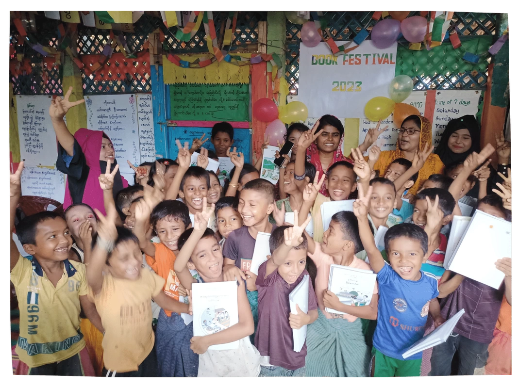 Children in a colourful classroom in Bangladesh are smiling and making peace 'V' signs