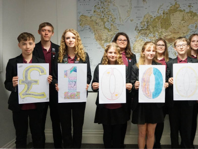 Students from Glebelands School visiting the COTE office standing in front of a world map holding up signs saying £10,000