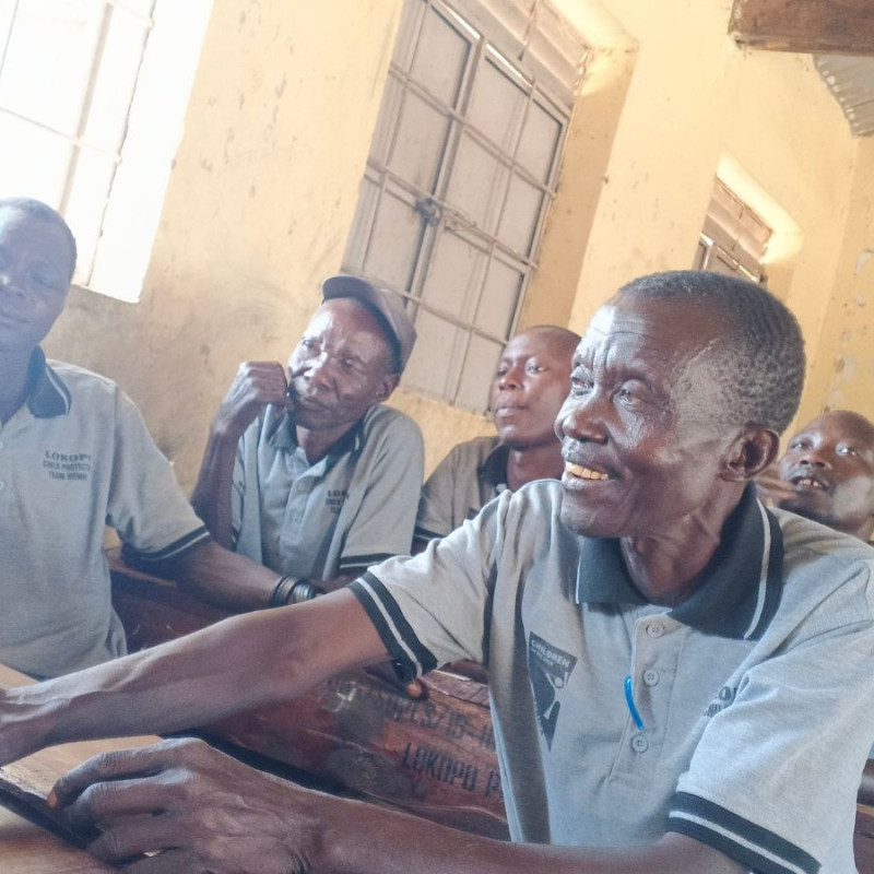 a Child Protection Team meeting in Karamoja, members are sat at desks listening to a speaker