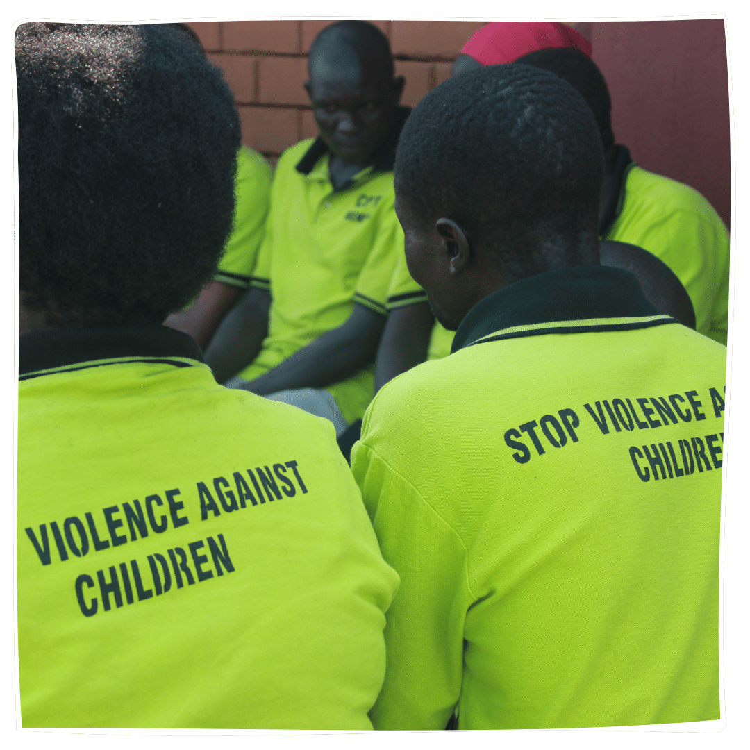 Child Protection Team members meeting wearing tshirts with 'stop violence against children' on the back