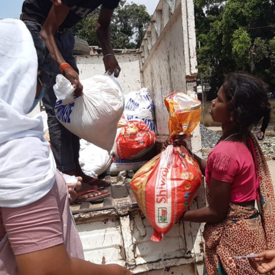 A girl of around ten years old is helping to take bags of food provision off the back of an open bed truck, helping with a food distribution in the middle of lockdown, Bihar State. 
