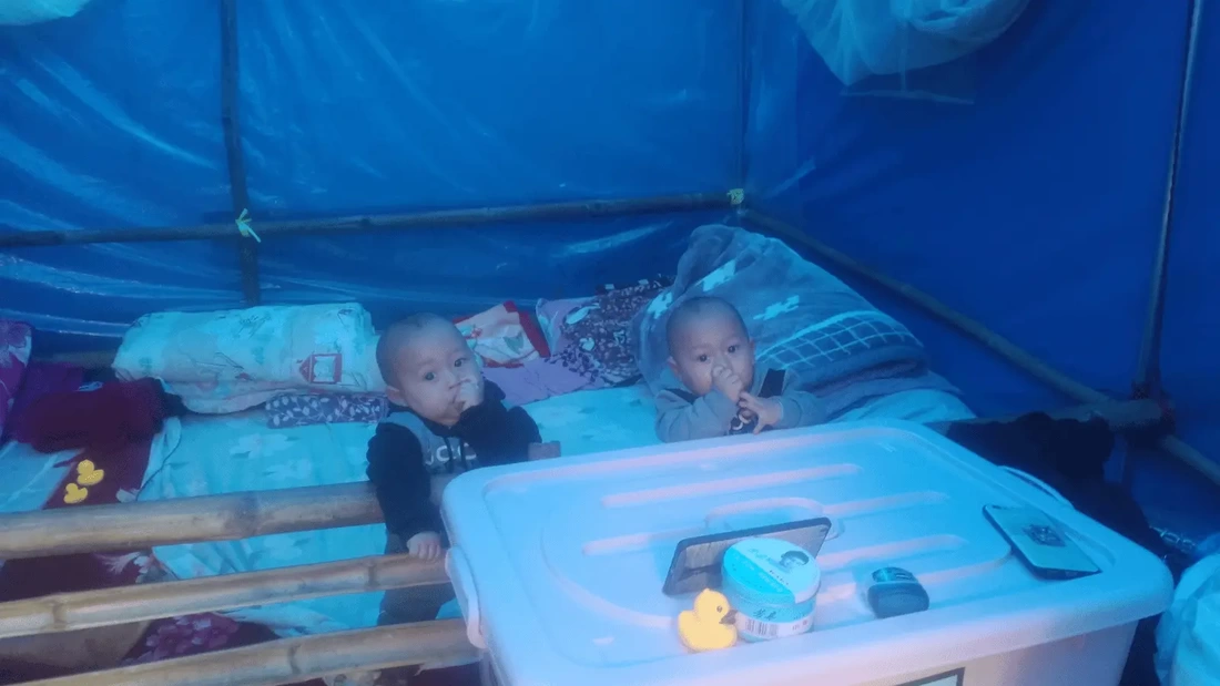 Two babies in a makeshift cot bed in a blue tent in Myanmar