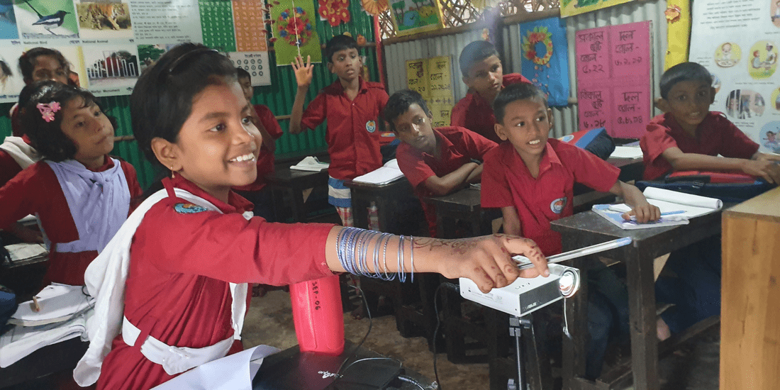 A classroom of happy Bangladeshi students sat at their desks