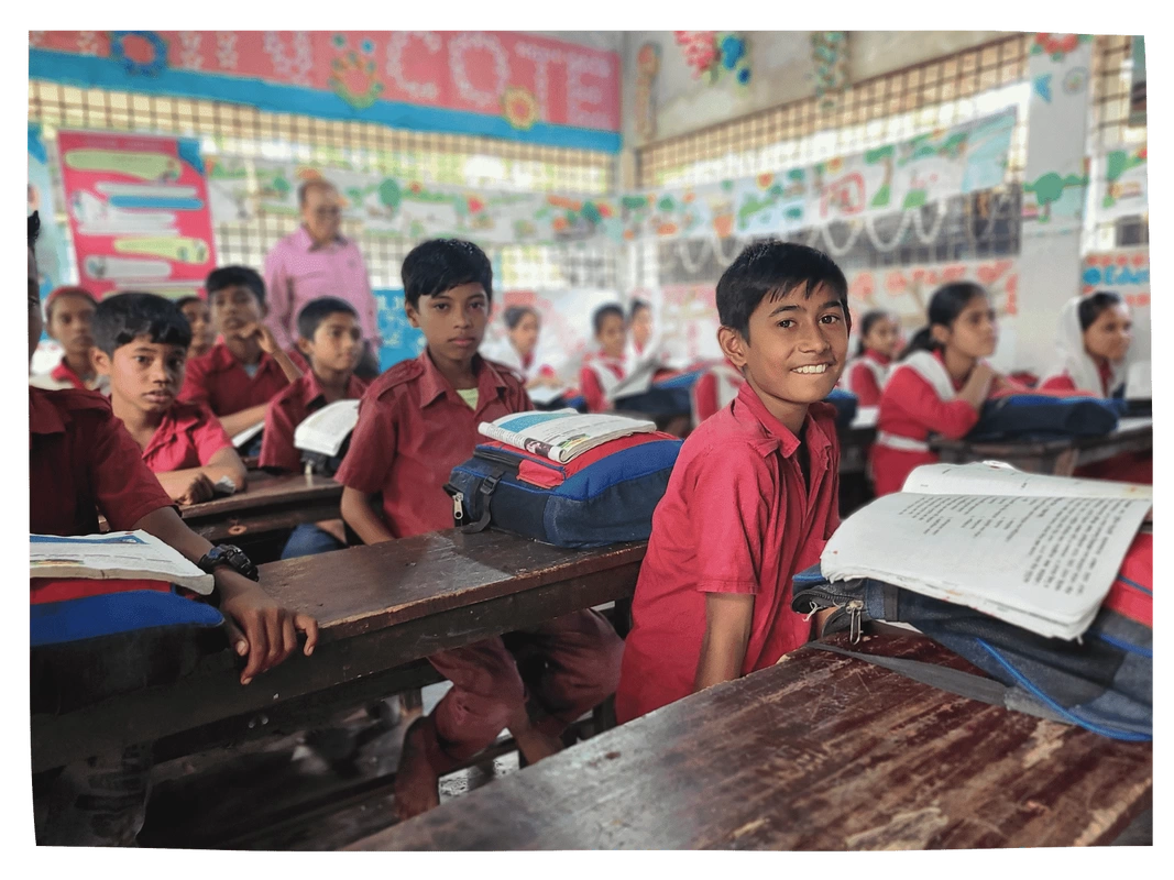 Children in red uniforms with bags and textbooks in their classroom