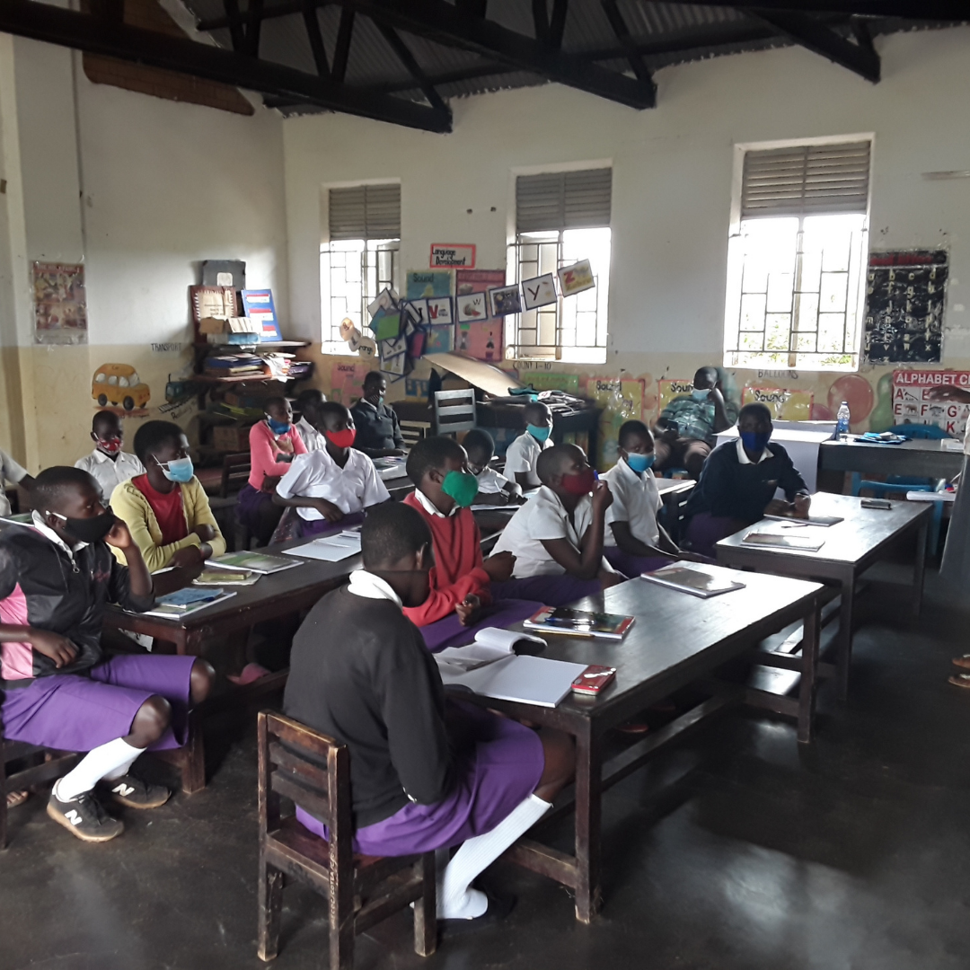 Child protection team members in Uganda gather in a classroom around tables