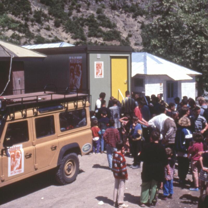 An old photo from the Kosovan refugee crisis showing mobile shower units arriving with a group of refugees. 