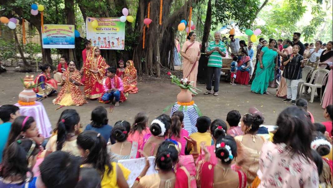 Girls from our learning centres in India gather outside to celebrate under a large tree, there are coloured balloons and girls dressed up ready to perform a dance