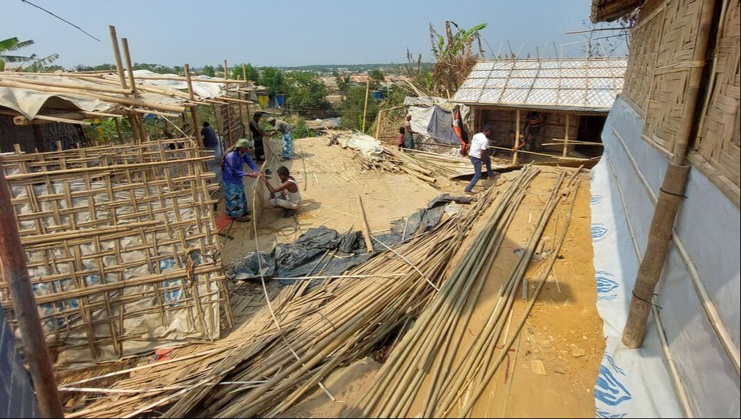 In Kutupalong camp, a small area is filled with long bamboo canes, which are being constructed together by workers.
