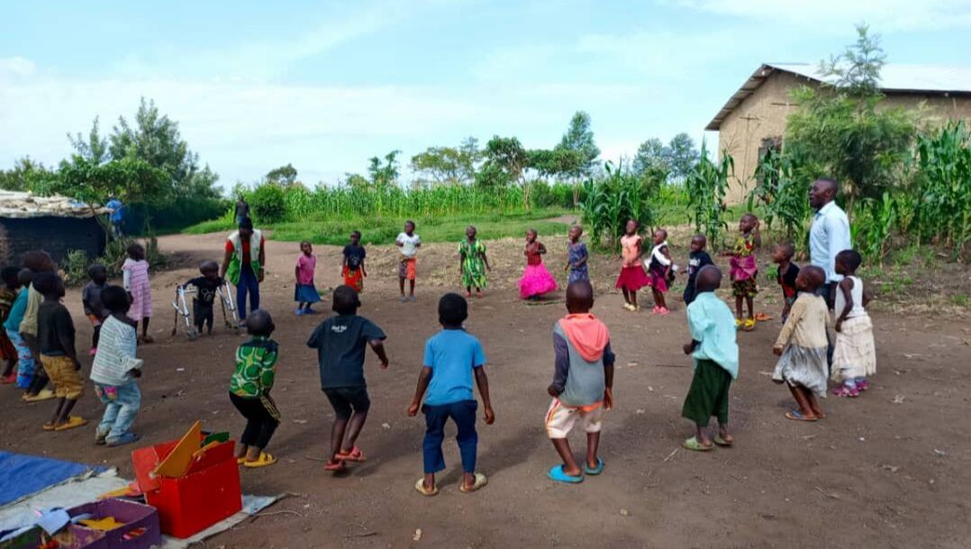 Group of Congolese children gathered in a circle jumping during their cluster class