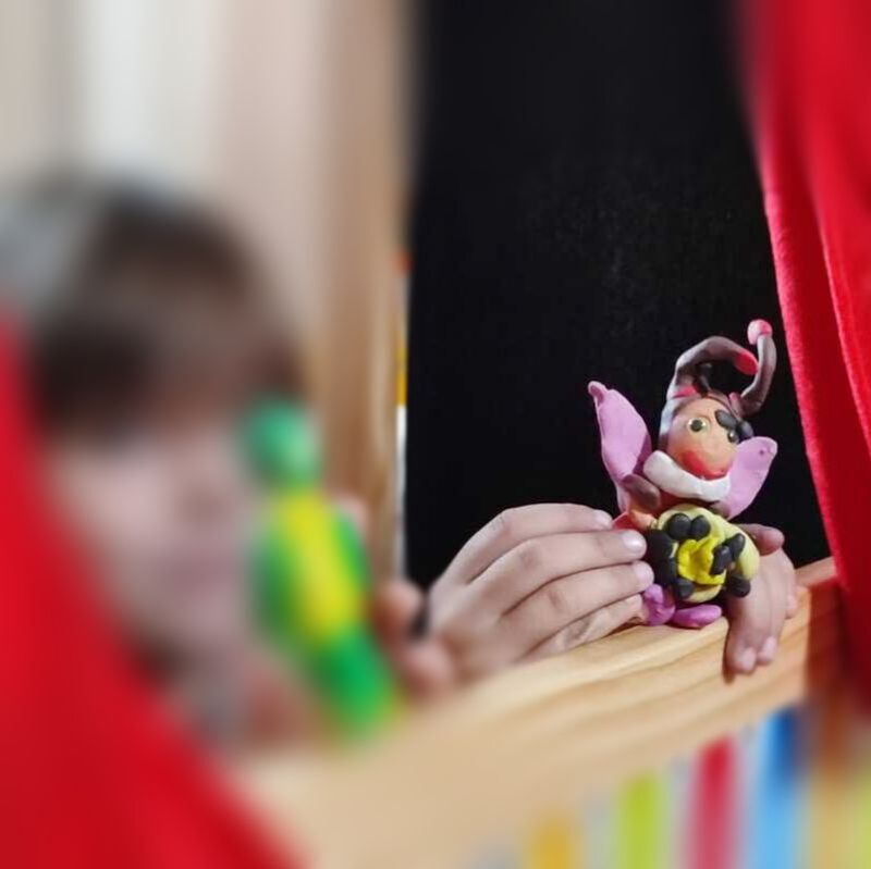 Child (image of face blurred) playing with puppet show. 