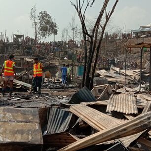 Two men survey the damage done to peoples' homes in Kutupalong refugee camp following devastating fires in March 2022