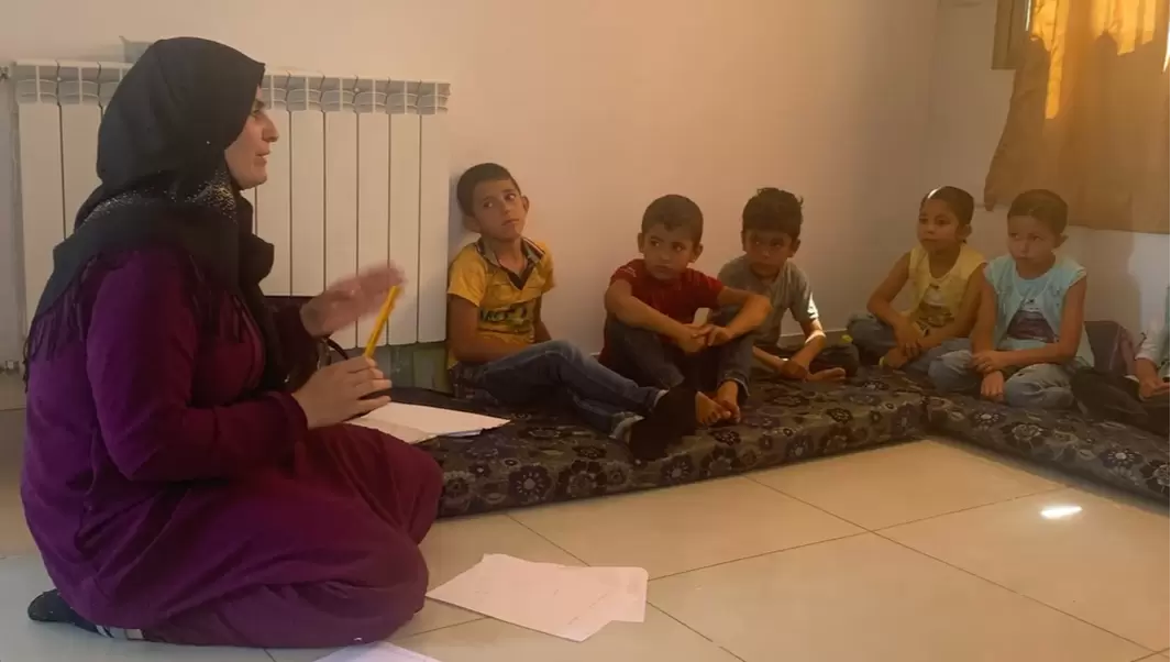 Mayassa is teaching a small group of younger children in a classroom