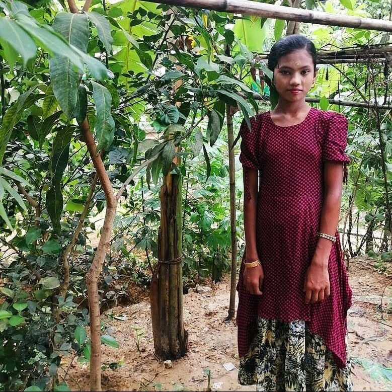 11 year old Monowara stood in her school garden, smiling at the camera