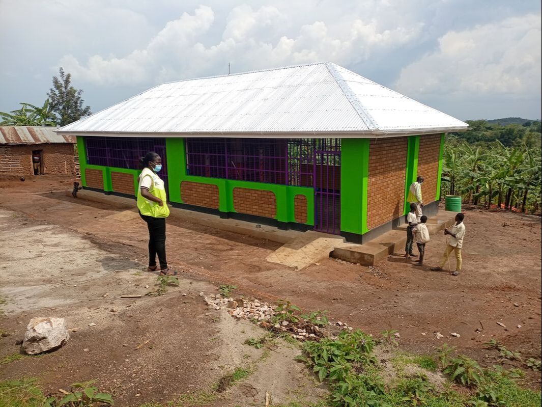 A brand new school building made of bricks with bright green pillars and purple metal windows. 