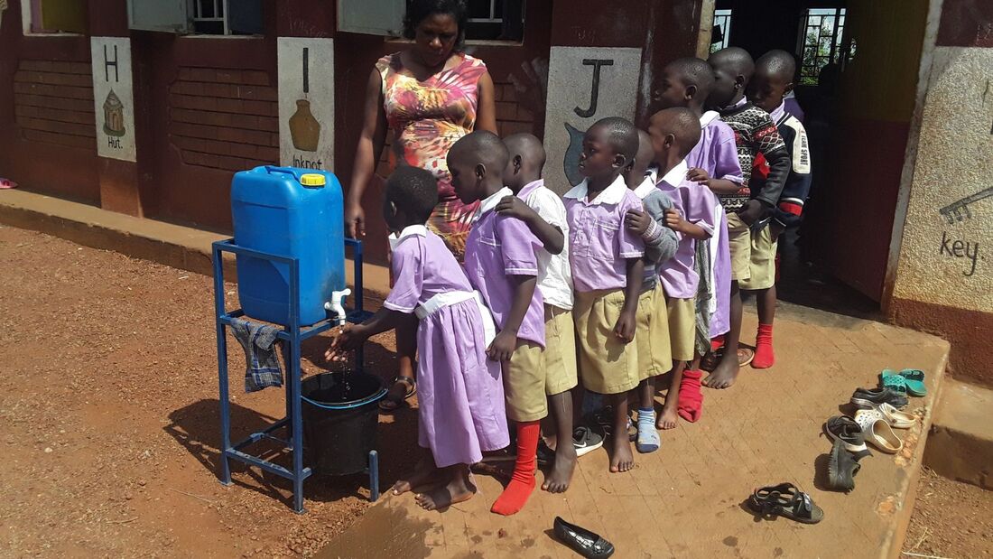 Ugandan preschool children queuing up outside their classroom to wash their hands 