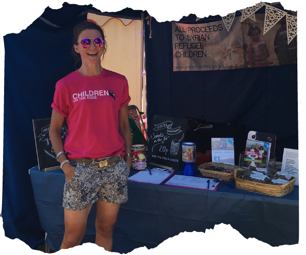Woman in sunglasses wearing a children on the edge tshirt standing in front of a fundraising stall
