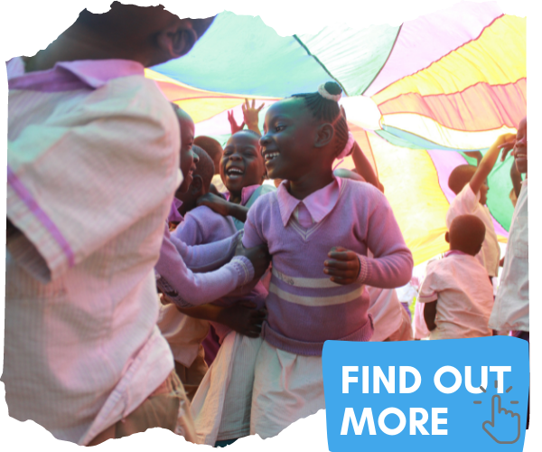 Group of Ugandan children are laughing under a brightly coloured parachute as they enjoy a game. They are wearing lilac and white uniforms. You can click this image to be taken to a page to find out more. 