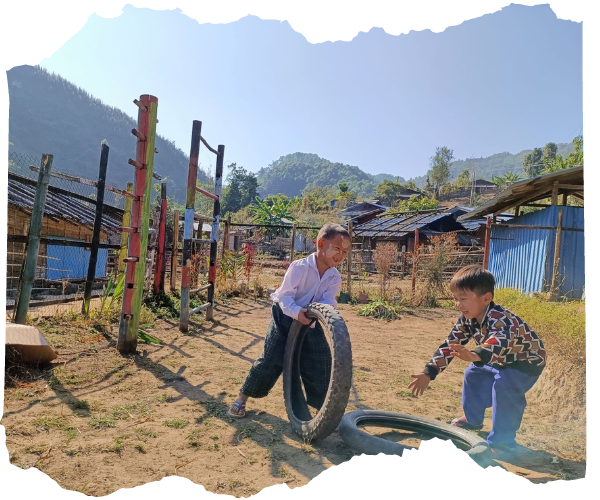 Two children in Kachin State playing with tyres in their school playground
