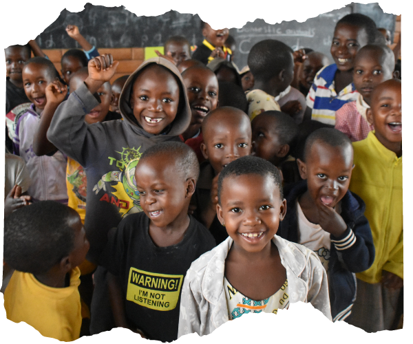 Young Congolese refugee children are stood together in their classroom, they are smiling and looking at the camera