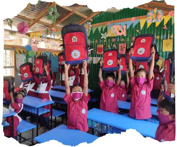 Bangladeshi children in a school classroom holding up their new school bags