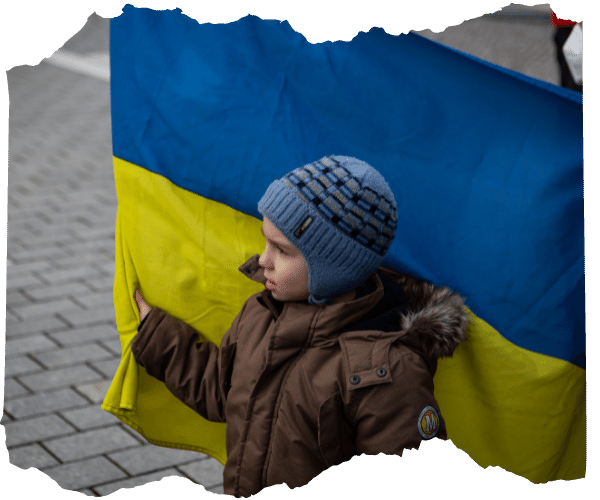 Young Ukrainian boy standing in front of blue and yellow Ukraine flag