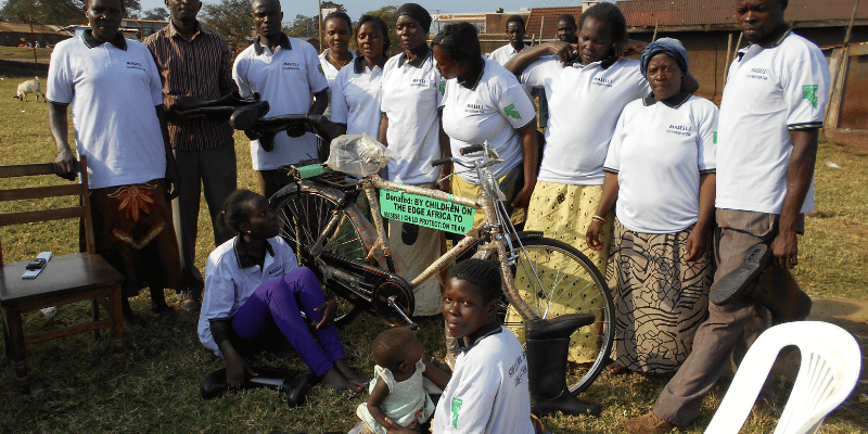 Child Protection Team stood together in front of their brand new team bike in Jinja, Uganda