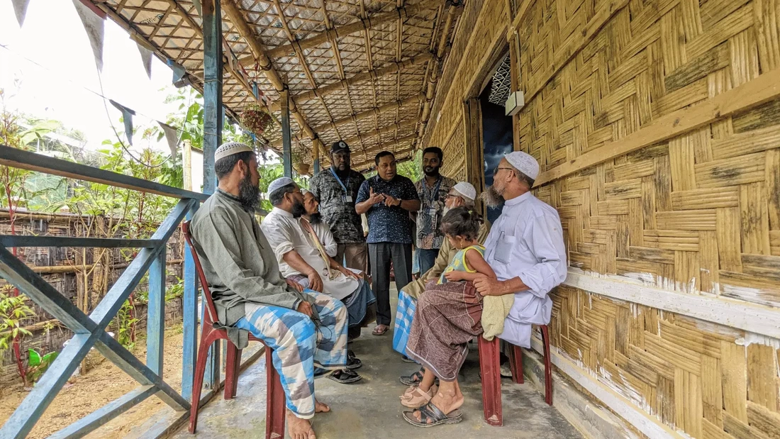 A group of Imans sat on a verandah are talking with staff from Mukti Cox's Bazar