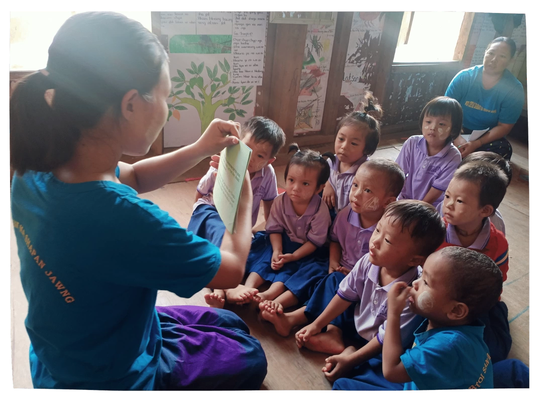Children listening to a story read by their teacher in Kachin