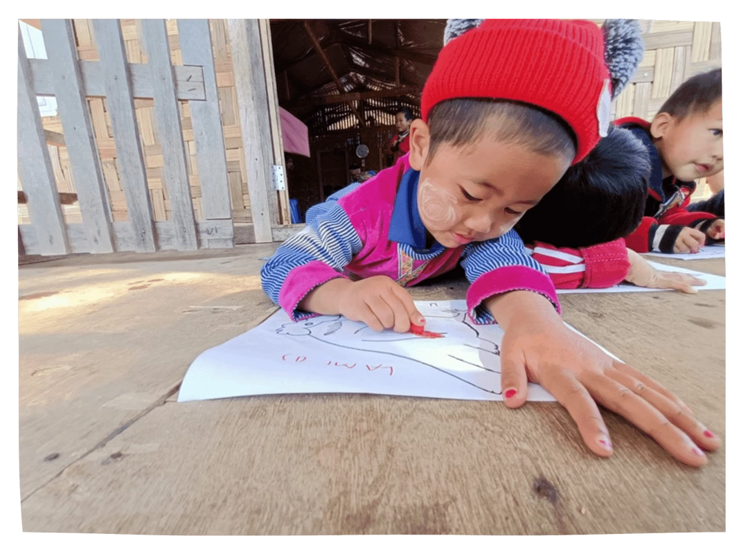 Preschooler in Kachin drawng with a crayon