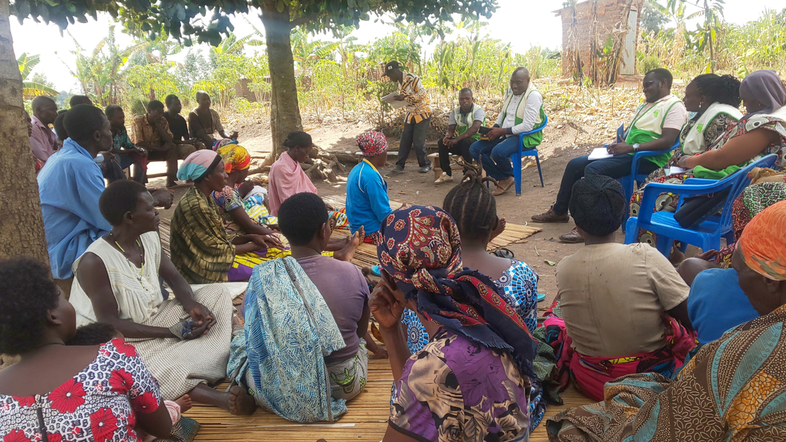 Congolese parents gather under trees for a training meeting with COTE staff