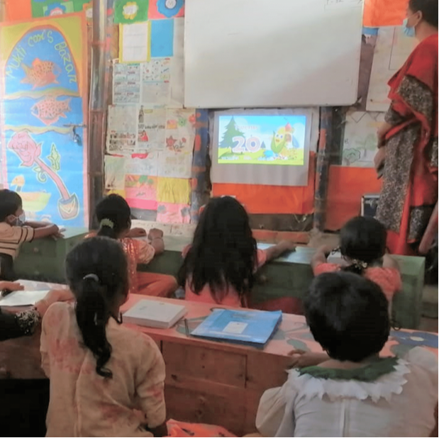 Children in Bangladesh watching a digital cartoon lesson on a projector screen in their classroom