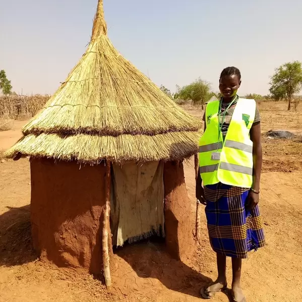 CPT Member Maria standing next to a latrine she built at her home after CPT training on health and hygiene