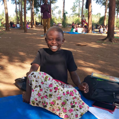 Sifa smiling at a cluster class outside under the trees