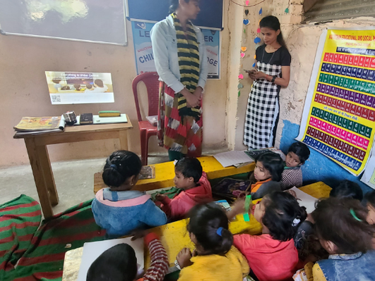 Teachers in small Indian classroom are working out how to use the new projector as young children look on from their desks