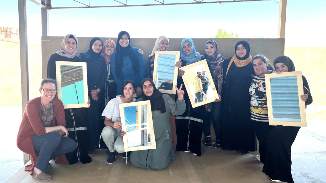 Group of female students holding up mirrored frames they have made
