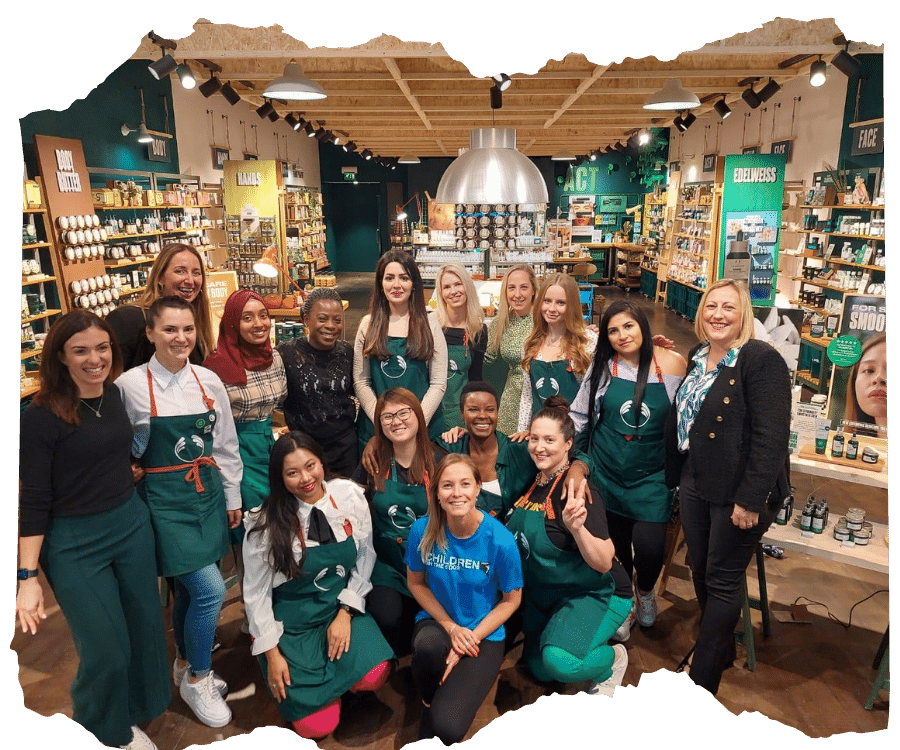 A group of staff from pictured wearing green aprons in a The Body Shop store