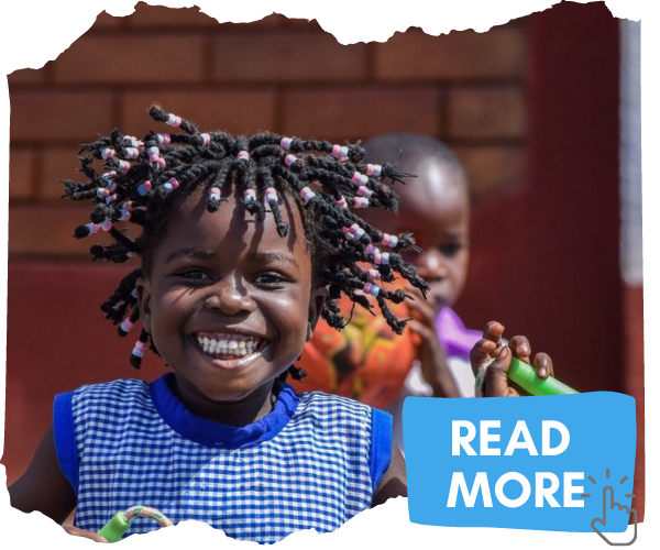 Ugandan girl of around 7 years smiling at the camera. She has braided hair with pink and white braids in it. She is outside a Early Childhood Development centre and playing with her friends. Attached button image invites you to click to read more. 